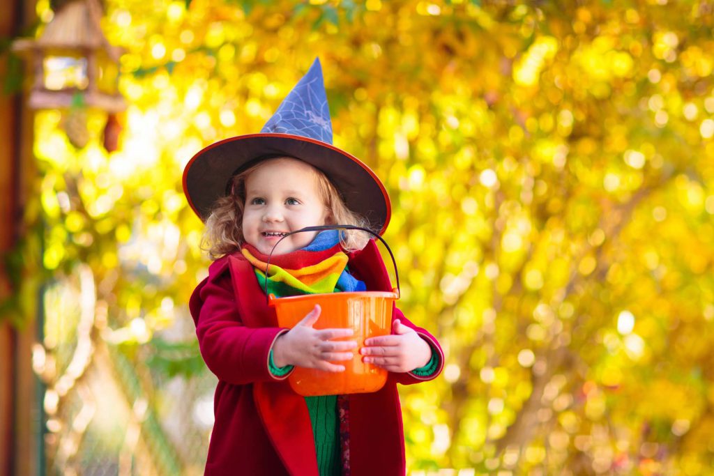 Child in Halloween costume holding a candy bucket, symbolizing Halloween safety tips for children.