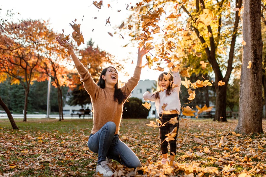 A mother and child playing in fallen leaves