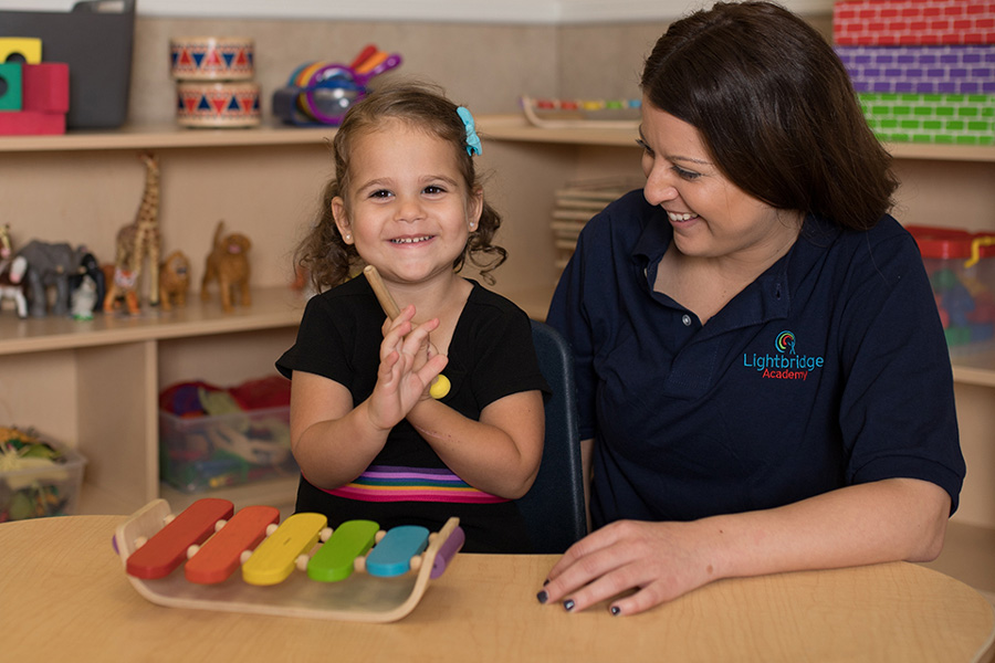 A little girl and teacher playing with musical instraments